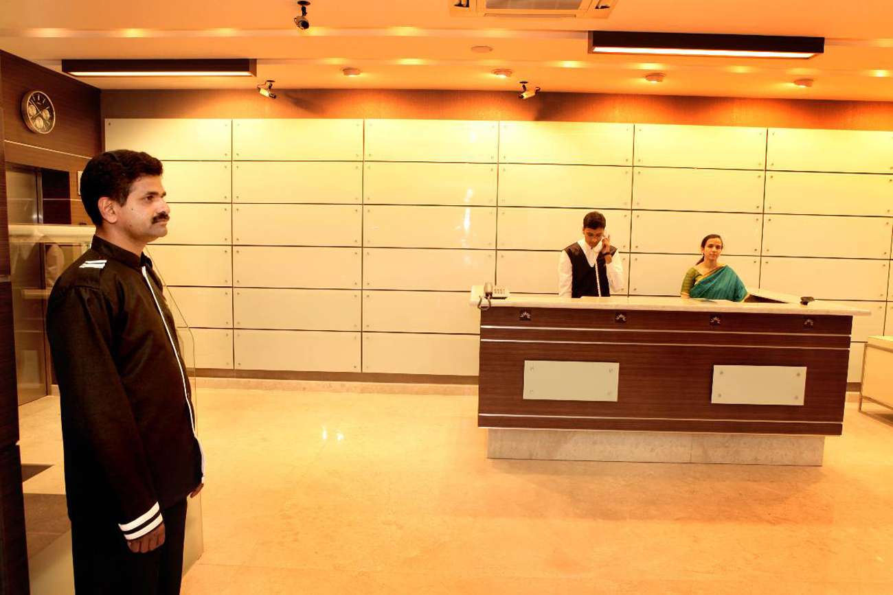 Architect-designed modern hotel lobby in Tamilnadu featuring a sleek reception counter with backlit glass wall paneling, ambient lighting, and a minimalist layout.
