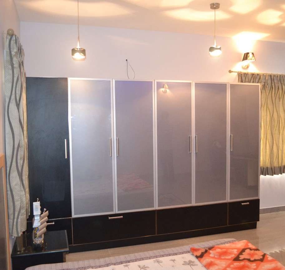 Modern bedroom wardrobe with black and grey color scheme - glass shutters and acrylic shutters, aluminum handles — custom modular wardrobe design and execution by interior designers in Thindal, Erode, Tamilnadu, India.