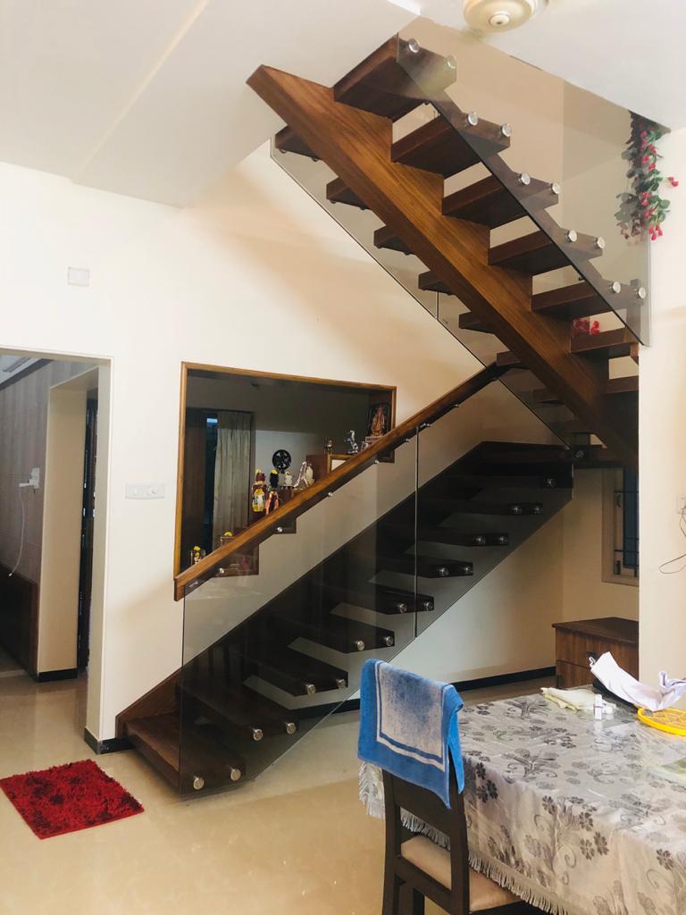 Modern wooden staircase with sleek glass railing in a duplex home interior at Salem – designed and executed by professional interior designers and contractors for a contemporary and open living space.