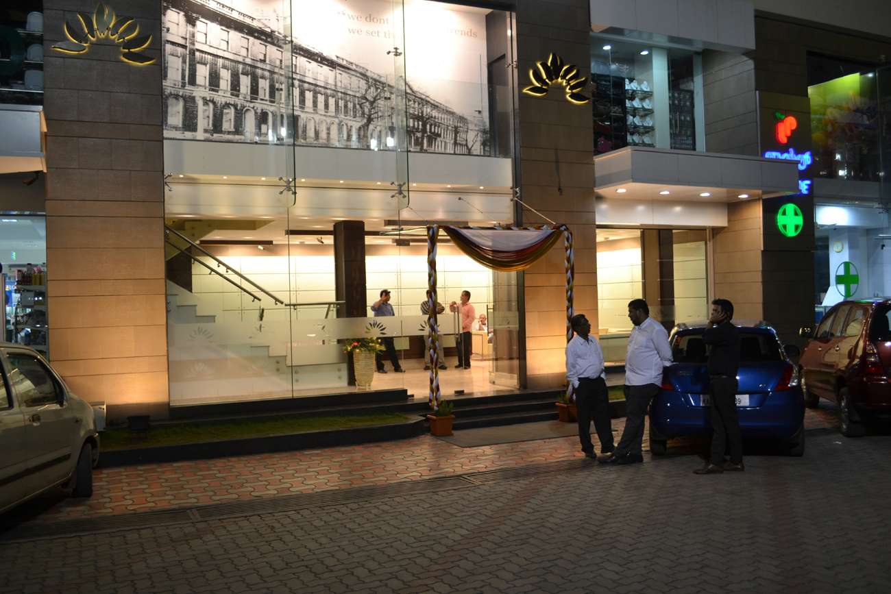Elegant hotel entrance with full glass façade and illuminated signage at Salem, Tamilnadu — featuring custom-designed lobby interiors, staircase with stainless steel railing, and professional-grade architectural lighting by expert hotel interior contractors and manufacturers.