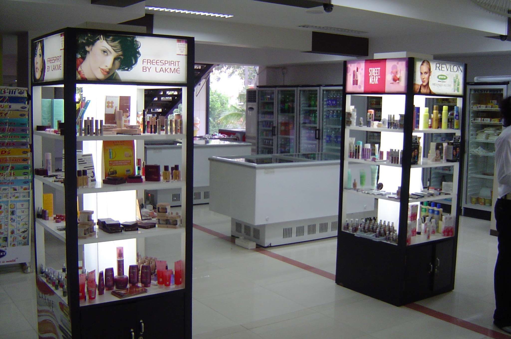 Cosmetic product display counters in a retail store at Salem, Tamilnadu, featuring illuminated shelves showcasing beauty brands like Lakmé, Revlon, and Street Wear — highlighting retail interior design and display fixture solutions by interior contractors, designers, and store fit-out specialists.