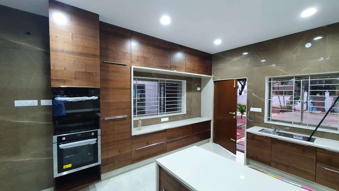 Elegant modular kitchen in RS Puram, Coimbatore with walnut-finish cabinets, integrated appliances, Fully designed, manufactured, and installed by our expert interior and furniture team.