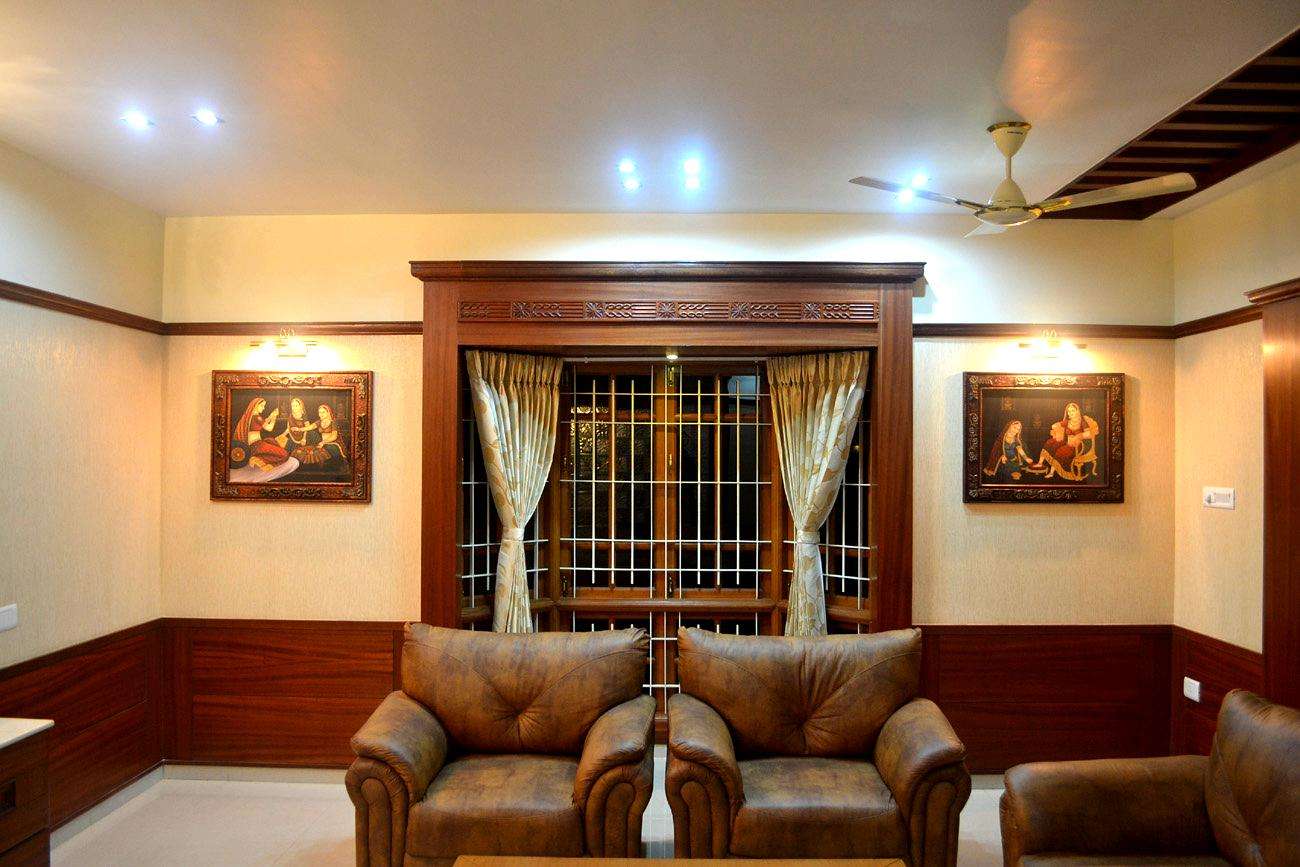 Traditional living room with rich teak wood interiors, classic window frame detailing, and ethnic artwork, located on Perundurai Road, Erode. Fully designed, manufactured, and installed by our expert interior and furniture team.