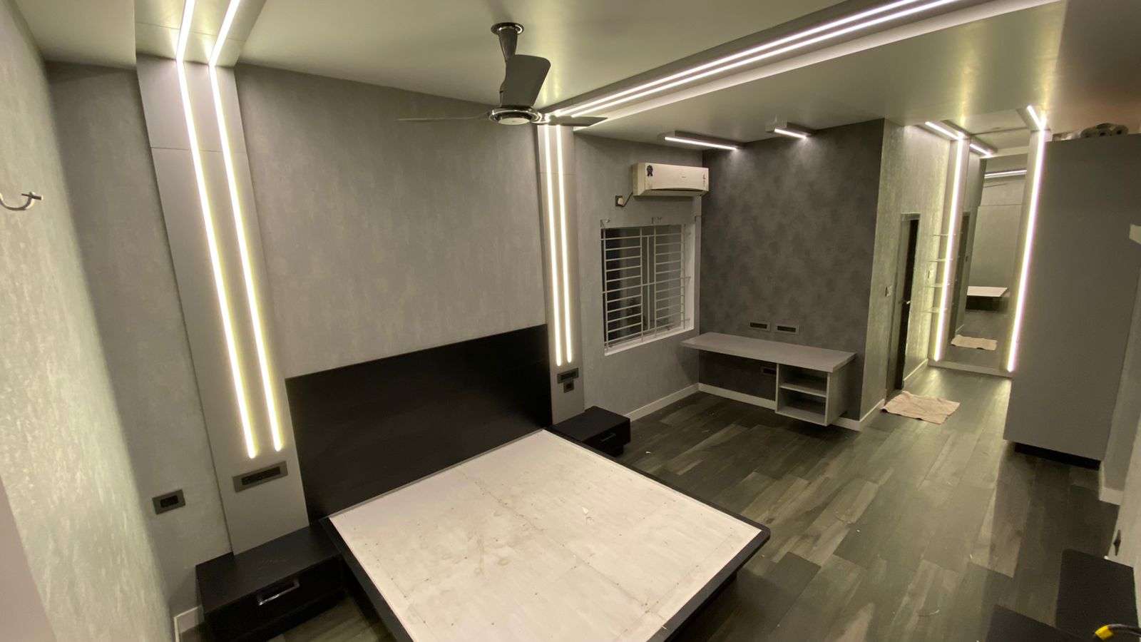 Stylish black and grey bedroom interior with embedded strip lighting, sliding wardrobes, and functional woodwork designed for a young college student at Peelamedu, Coimbatore.