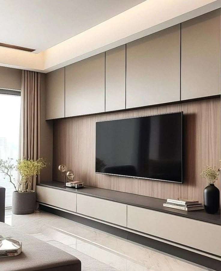 Contemporary living room with a sleek wall-mounted TV unit, matte finish cabinetry, and wood-textured paneling is designed, manufactured, and installed by our expert interior and furniture team at a residence in Tiruppur, Tamil Nadu.