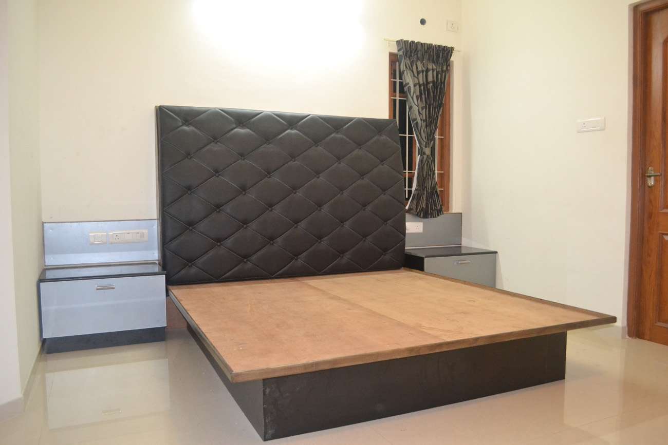 Modern bedroom with a king-sized cot featuring a black diamond-patterned upholstered headboard and metallic finish side units. Shot at a residence in Pollachi, Tamilnadu.
