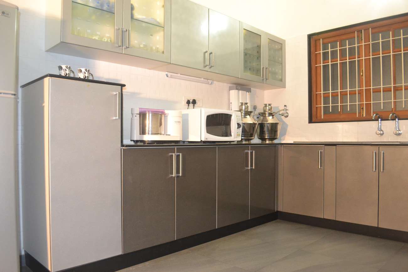 Black and grey modular kitchen in Kothagiri, Coimbatore with glass shutters, inside cabinet lighting and sleek modern storage. Fully designed, manufactured, and installed by our expert interior and furniture team. Fully designed, manufactured, and installed by our expert interior and furniture team.